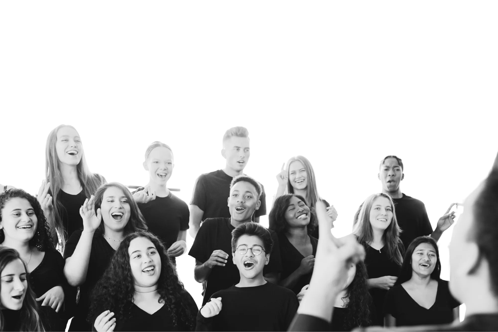 A choir mid-song, faces lifted, conductor's hand raised in the foreground
